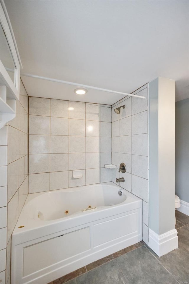 bathroom with tile patterned flooring, toilet, and tiled shower / bath