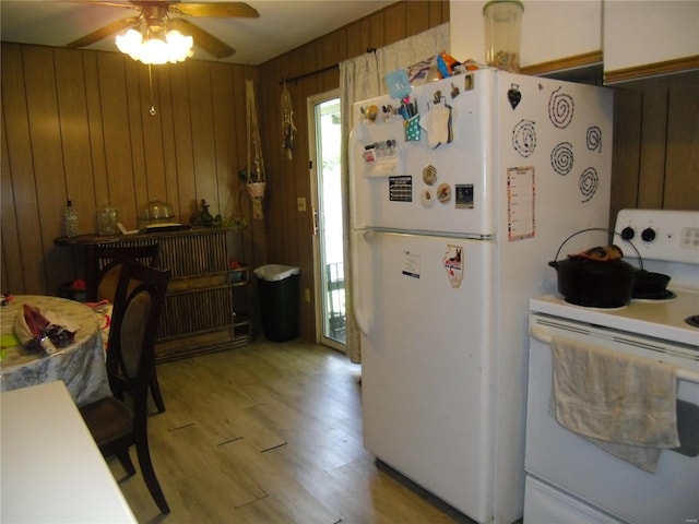 kitchen featuring ceiling fan, light hardwood / wood-style flooring, wooden walls, and white appliances