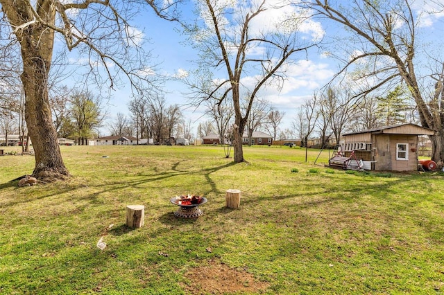 view of yard featuring an outdoor structure and a fire pit