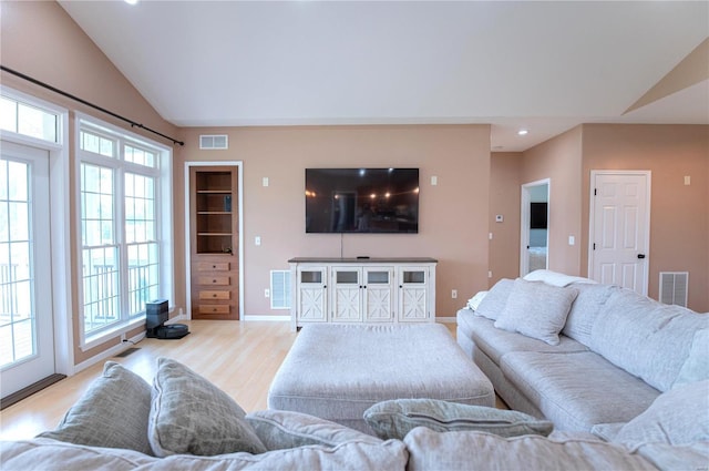 living room featuring lofted ceiling, light hardwood / wood-style floors, and plenty of natural light