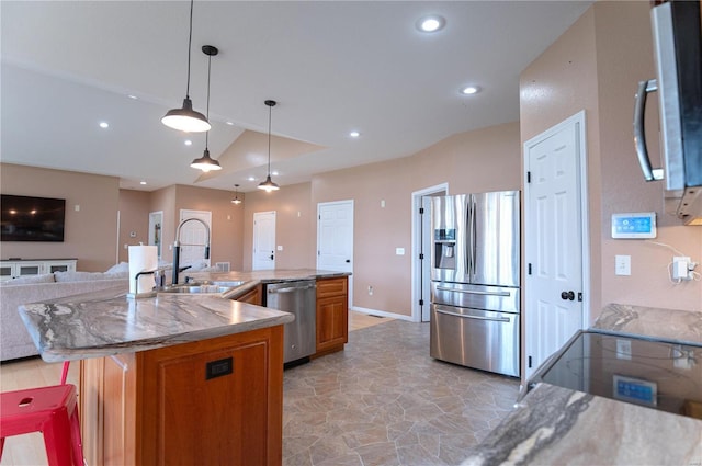 kitchen featuring vaulted ceiling, decorative light fixtures, sink, a kitchen island with sink, and stainless steel appliances