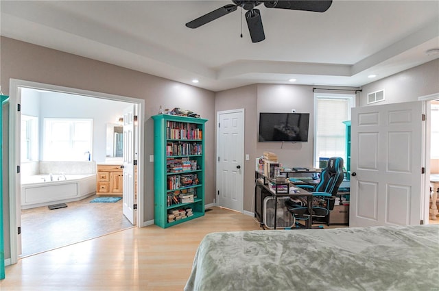 bedroom featuring ensuite bath, wood-type flooring, and multiple windows