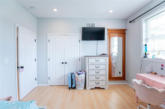 bedroom with light hardwood / wood-style floors and a closet