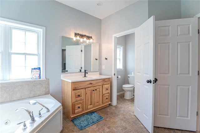 bathroom with vanity, a tub to relax in, plenty of natural light, and toilet