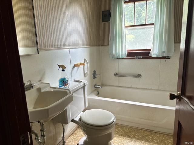 full bathroom with toilet, a washtub, a sink, and tile patterned floors