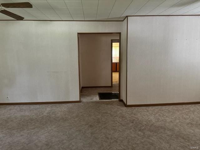 empty room featuring carpet, baseboards, and a ceiling fan