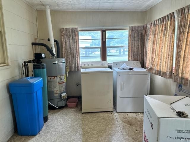 clothes washing area with concrete block wall, laundry area, washing machine and dryer, and water heater