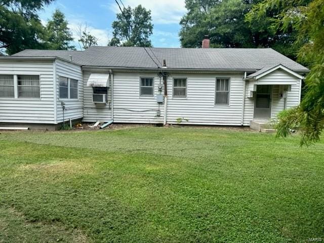 rear view of property featuring cooling unit, a yard, and a chimney