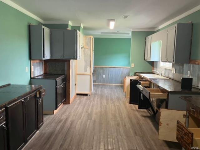 kitchen featuring crown molding, light wood-type flooring, sink, and wooden walls