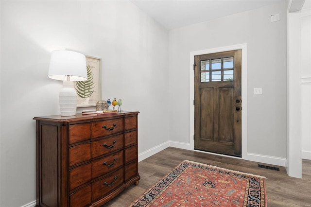 foyer featuring baseboards, visible vents, and wood finished floors