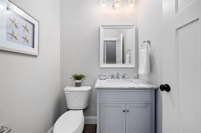 bathroom with baseboards, vanity, and toilet