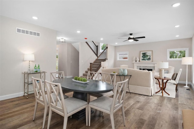 dining space featuring visible vents, wood finished floors, stairs, a fireplace, and recessed lighting