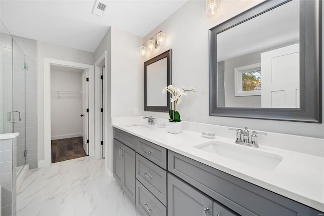 bathroom featuring marble finish floor, a stall shower, a sink, and visible vents