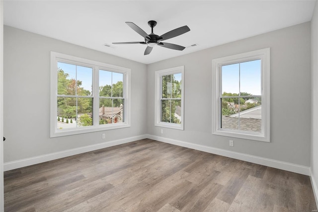 spare room featuring a ceiling fan, wood finished floors, visible vents, and baseboards