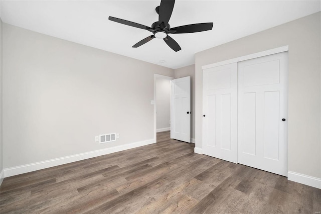 unfurnished bedroom with wood finished floors, a ceiling fan, visible vents, baseboards, and a closet