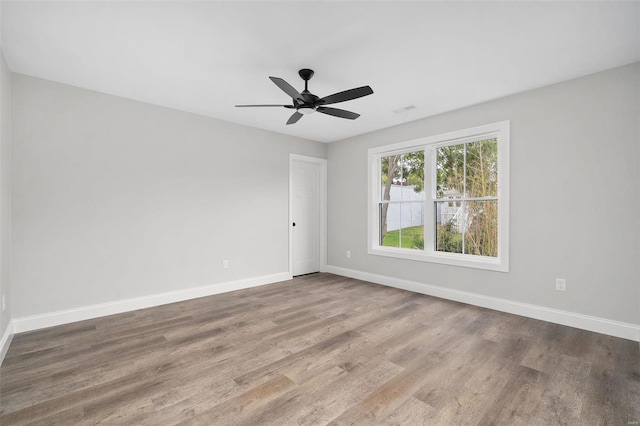 spare room featuring wood finished floors, a ceiling fan, and baseboards