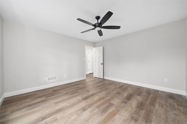 spare room featuring baseboards, visible vents, ceiling fan, and wood finished floors