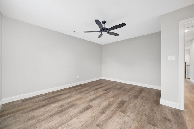 spare room featuring visible vents, ceiling fan, baseboards, and wood finished floors