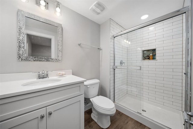 bathroom with toilet, wood finished floors, vanity, visible vents, and a shower stall