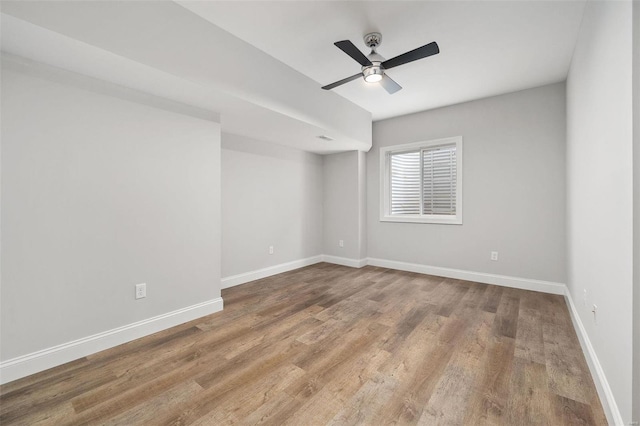 empty room featuring a ceiling fan, baseboards, and wood finished floors