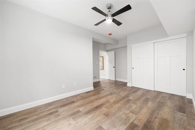 unfurnished bedroom with visible vents, baseboards, a ceiling fan, wood finished floors, and a closet