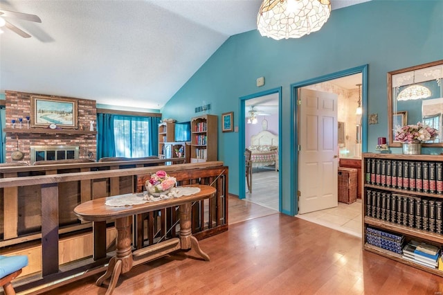 dining area featuring ceiling fan, light hardwood / wood-style flooring, brick wall, and lofted ceiling