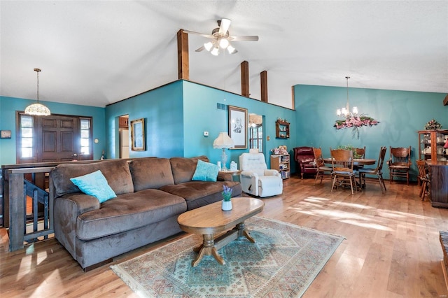 living room with ceiling fan with notable chandelier, vaulted ceiling, and light hardwood / wood-style floors