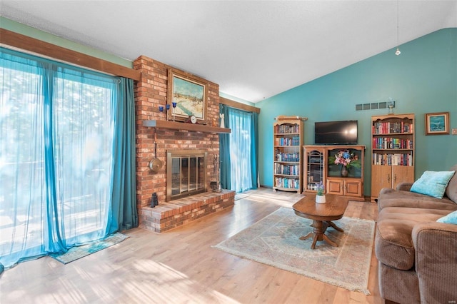 living room with a fireplace, light wood-type flooring, and a healthy amount of sunlight