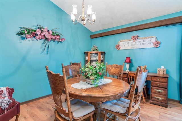 dining area with light hardwood / wood-style floors, vaulted ceiling, a textured ceiling, and a chandelier