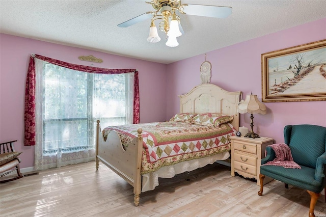 bedroom with a textured ceiling, light hardwood / wood-style flooring, and ceiling fan