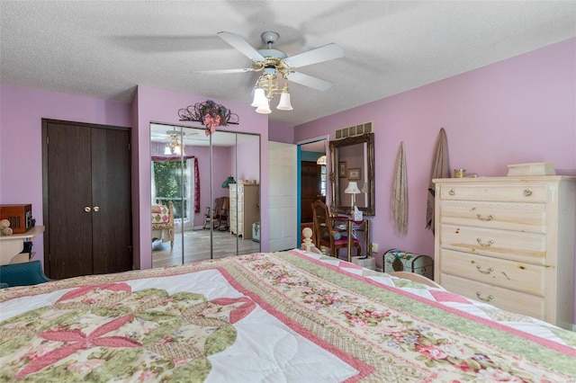 bedroom with ceiling fan, a textured ceiling, and multiple closets