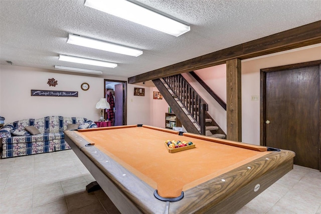 game room with a textured ceiling, light tile patterned floors, and pool table