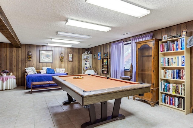 rec room with pool table, wood walls, a textured ceiling, and light tile patterned floors