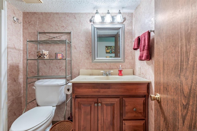 bathroom with a textured ceiling, vanity, and toilet