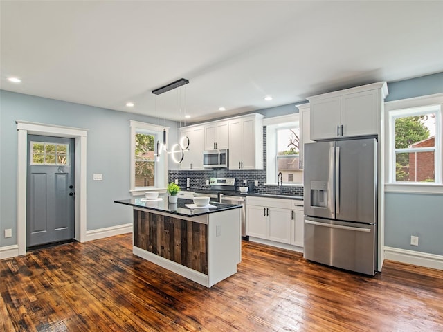 kitchen with dark hardwood / wood-style floors, stainless steel appliances, a healthy amount of sunlight, and decorative light fixtures