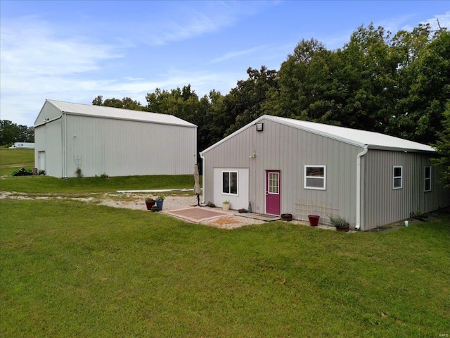 back of property with a yard and an outbuilding