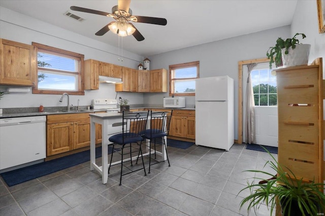 kitchen featuring visible vents, under cabinet range hood, white appliances, a ceiling fan, and a sink