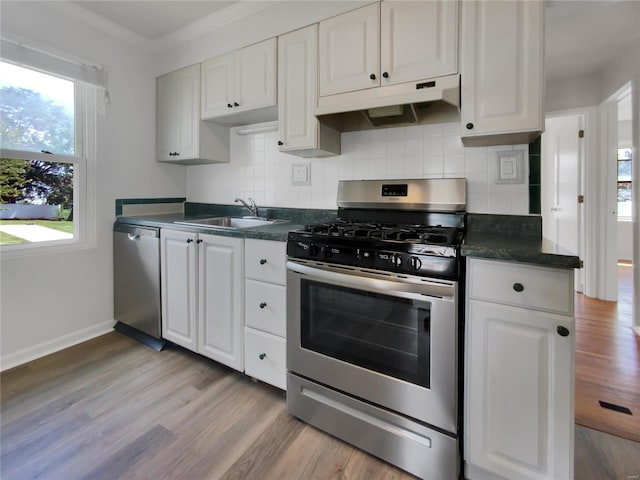 kitchen with sink, appliances with stainless steel finishes, white cabinetry, tasteful backsplash, and light hardwood / wood-style floors