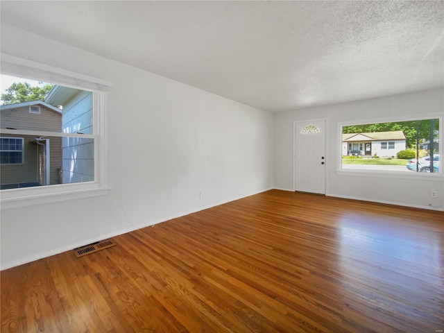 empty room with lofted ceiling, dark hardwood / wood-style flooring, and a textured ceiling