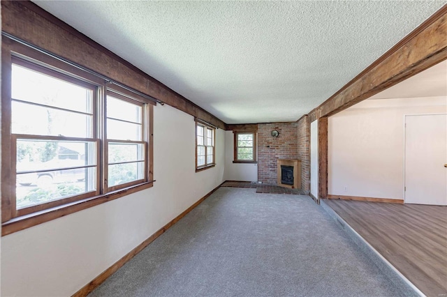 unfurnished living room with carpet floors, a brick fireplace, and a textured ceiling