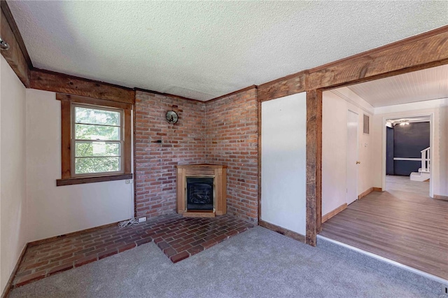 unfurnished living room with a brick fireplace, a textured ceiling, and carpet flooring