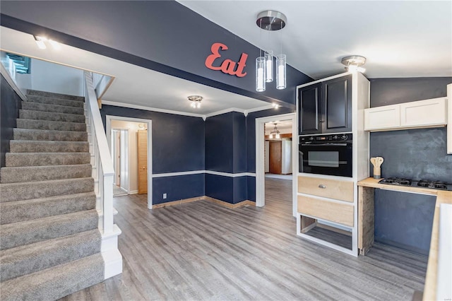 kitchen with black appliances, white cabinetry, decorative light fixtures, light hardwood / wood-style flooring, and ornamental molding