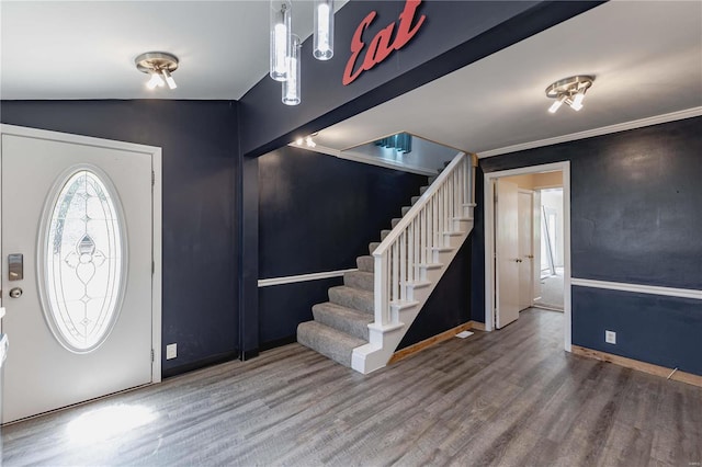 foyer with hardwood / wood-style flooring, ornamental molding, and vaulted ceiling