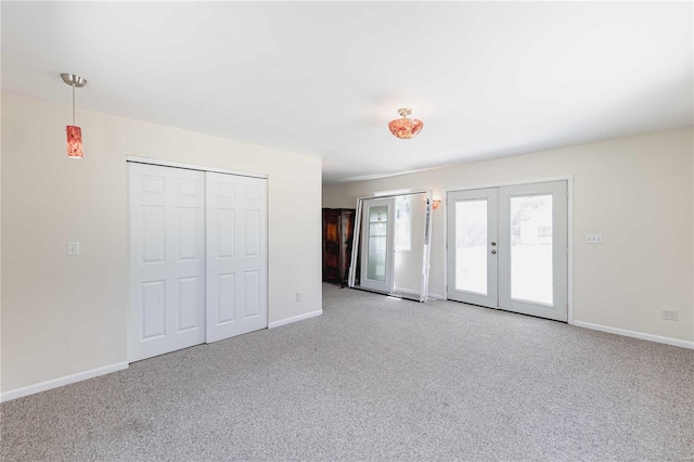 unfurnished bedroom with light colored carpet, a closet, and french doors