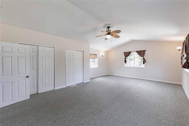 unfurnished bedroom with ceiling fan, carpet, multiple closets, and vaulted ceiling