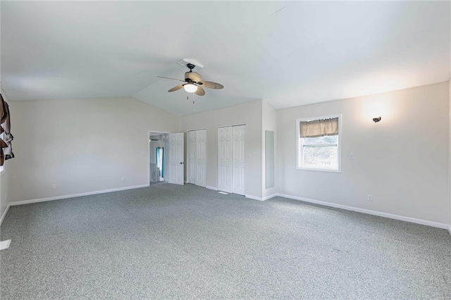 unfurnished bedroom featuring multiple closets, carpet flooring, vaulted ceiling, and ceiling fan