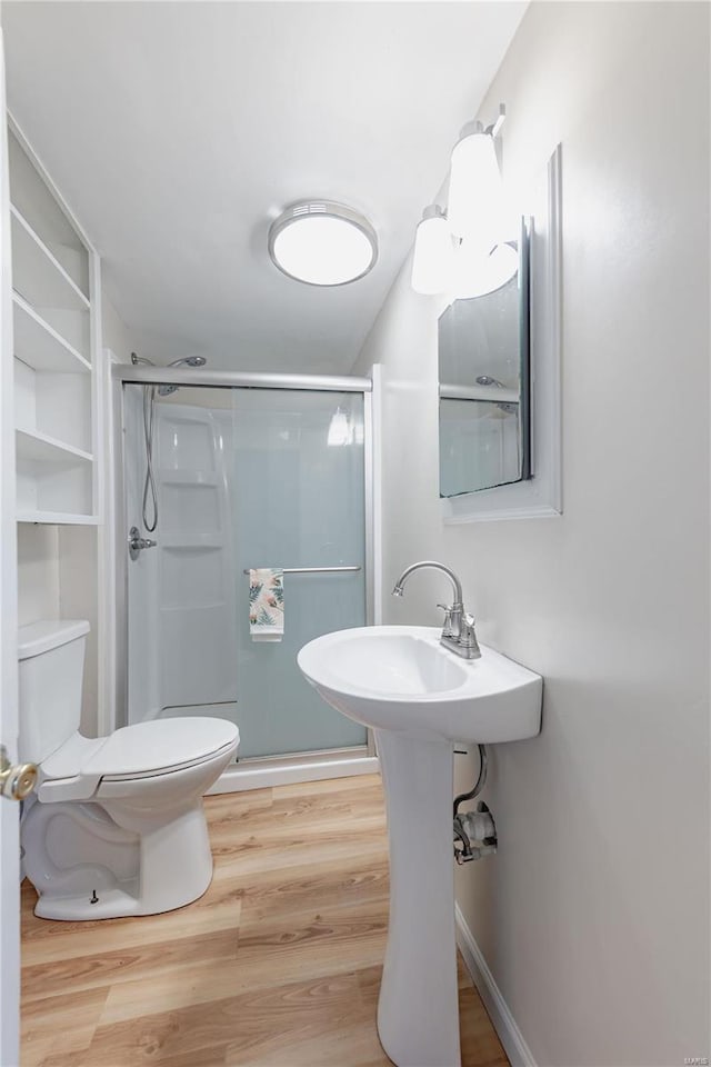 bathroom featuring toilet, hardwood / wood-style floors, and a shower with door