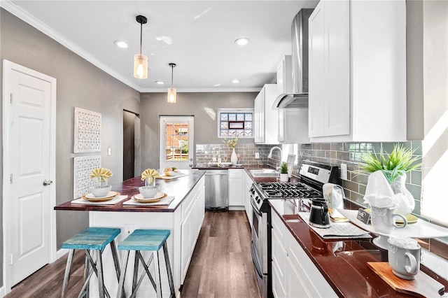 kitchen with dark hardwood / wood-style flooring, appliances with stainless steel finishes, pendant lighting, crown molding, and sink