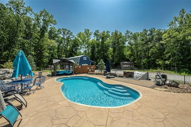 view of swimming pool with a shed and a patio