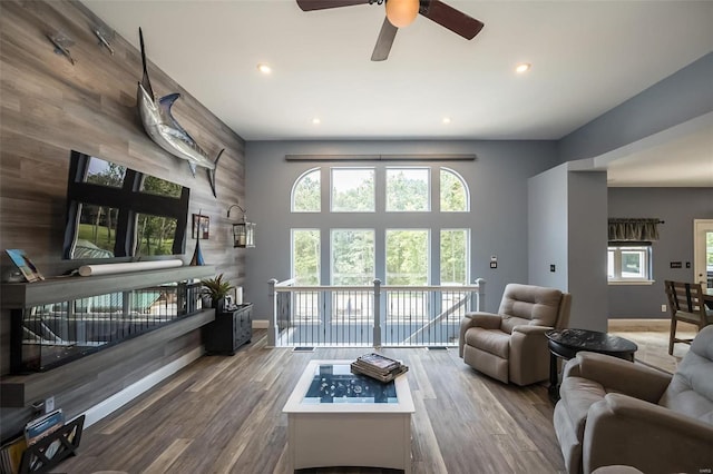 living room featuring wood walls, hardwood / wood-style floors, and ceiling fan